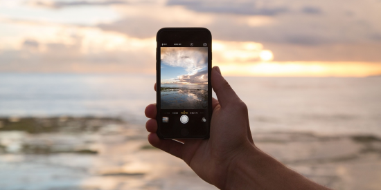 Eine Person fotografiert mit dem Smartphone den Sonnenuntergang