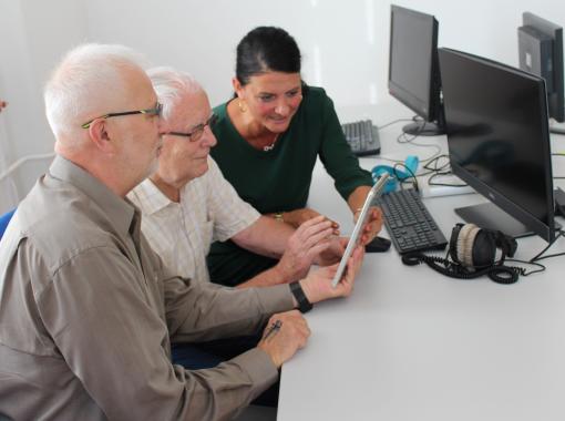 Lernsituation an einem Tablet mit zwei älteren Menschen 