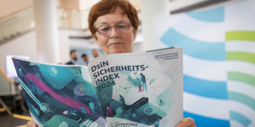 Eine Frau liest das Magazin "DsiN-Sicherheitsindex 2024". 