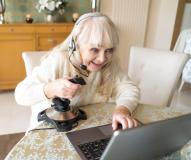 Frau sitzt mit Controller vor Laptop und spielt