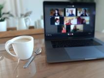 Man sieht eine Kaffeetasse neben einem offenen Laptop