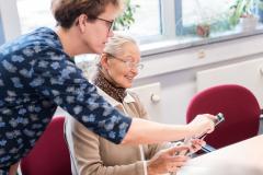 Frau erklärt älterer Frau ein Smartphone